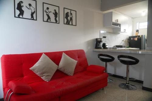 1 sofá rojo con 2 almohadas en la sala de estar en Cali te espera, en Cali