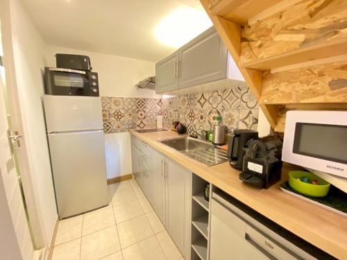 une cuisine avec un réfrigérateur blanc et un évier dans l'établissement L'Incontournable au cœur de Nîmes, à Nîmes