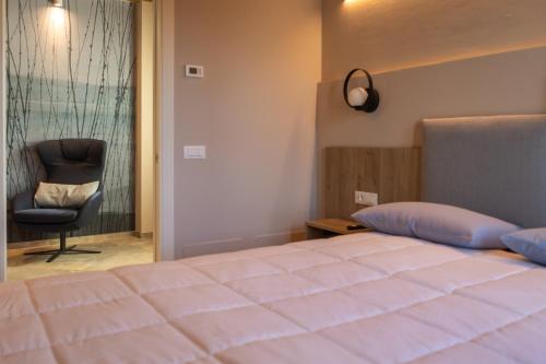 a bedroom with a bed and a chair next to a window at Pietralunga Resort in Fidenza