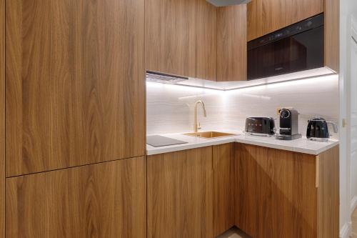 une cuisine avec des armoires en bois et un évier dans l'établissement Charming Pied-à-Terre Champs-Élysée, à Paris