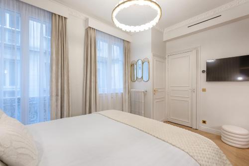 - une chambre blanche avec un grand lit et un lustre dans l'établissement Charming Pied-à-Terre Champs-Élysée, à Paris