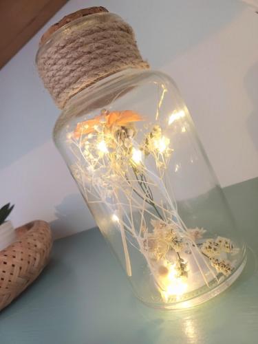 un pot en verre rempli de fleurs et de lumières sur une table dans l'établissement Le Green Center - Studio Cosy Plein Centre Ville, à Beauvais