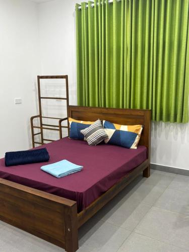 a bedroom with a wooden bed with a green curtain at The Nest Kandana in Kandana