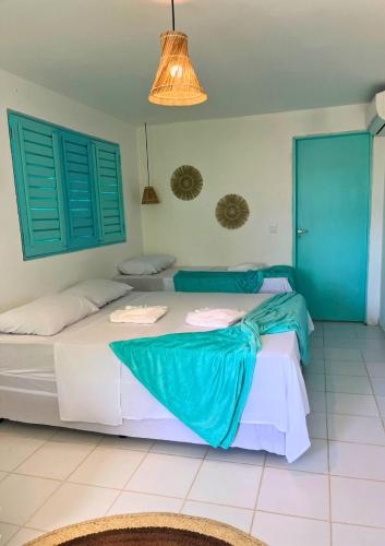 a bedroom with two beds with blue shutters at Amaly Pousada e Bistrô in Japaratinga