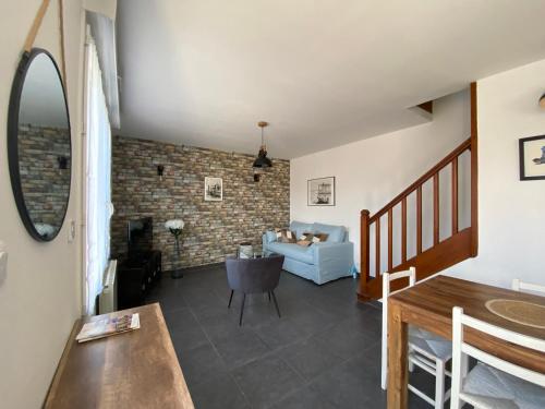 a living room with a blue couch and a brick wall at La Maison du Lavoir in Port-en-Bessin-Huppain