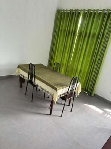 a table with two chairs in front of a green curtain at The Nest Kandana in Kandana