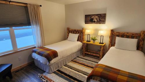a bedroom with two beds and a window at Beargrass Lodging & RV Resort in Hungry Horse