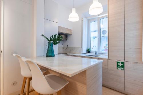 a kitchen with a counter and two white chairs at Madragoa Studio Zero in Lisbon