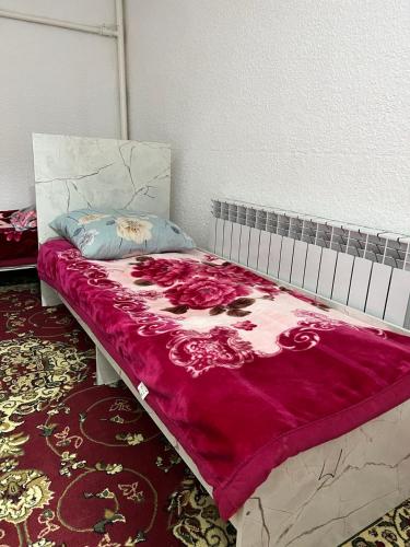a bed with a red and white blanket on it at Ethno homestay in Teploklyuchinskoye