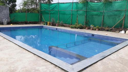 una piscina vuota con una recinzione verde di Green Valley Resort Villa ad Alibaug
