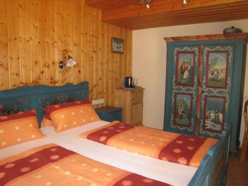 two beds in a room with wood paneled walls at Pension Landhaus Riedelstein in Drachselsried