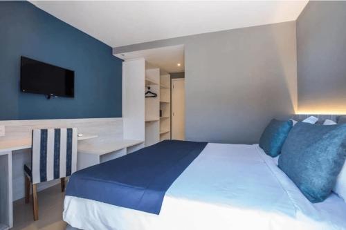 une chambre avec un lit, un bureau et une télévision dans l'établissement Flat 313 na melhor localização de Cabo Frio, à Cabo Frio