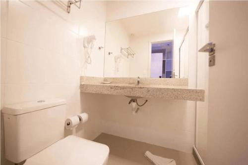 une salle de bains blanche avec toilettes et lavabo dans l'établissement Flat 313 na melhor localização de Cabo Frio, à Cabo Frio