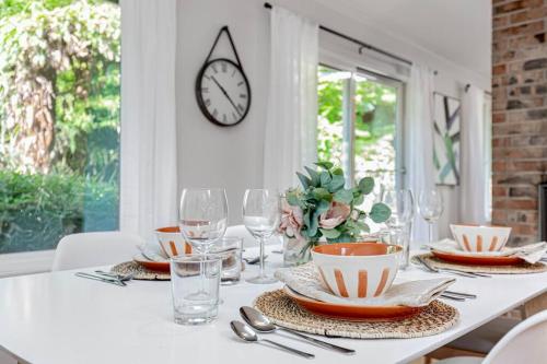 a table with plates and glasses and a clock on the wall at Mid-Century Modern Home - 3-Bedroom Rambler in Kirkland