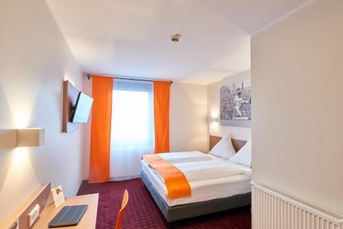 una camera d'albergo con letto e scrivania di McDreams Hotel Mönchengladbach a Mönchengladbach