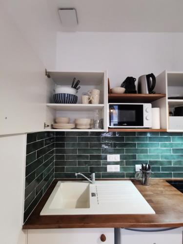 une cuisine avec un évier et du carrelage vert du métro dans l'établissement Cocon Verde Appartement T2, à Cognac