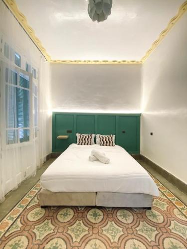 a bedroom with a large bed with a green headboard at Cozy apartment central Medina Tétouan 15 min airport sania ramel in Tetouan