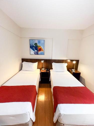 a hotel room with two beds with red sheets at Royal Design Savassi Hotel in Belo Horizonte