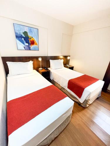 a hotel room with two beds with red and white sheets at Royal Design Savassi Hotel in Belo Horizonte