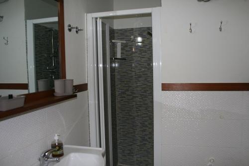 a bathroom with a sink and a shower with a mirror at African Lounge, Moradias Laranja in Prainha
