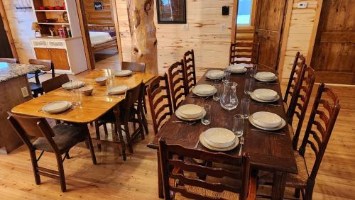 a long wooden table with chairs and plates and wine glasses at Beargrass Lodging & RV Resort in Hungry Horse
