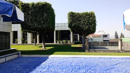 a house with trees in front of a yard at CASA MORADA 24 Personas alberca climatizada Burgos Cuernavaca in Cuernavaca