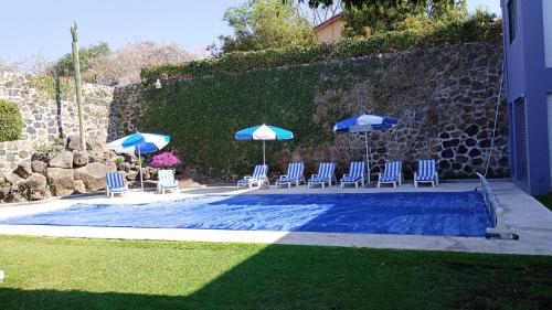 a group of chairs and umbrellas next to a pool at CASA MORADA 24 Personas alberca climatizada Burgos Cuernavaca in Cuernavaca