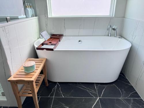a white bath tub in a bathroom with a wooden stool at The Beautiful 31 in Port Wentworth