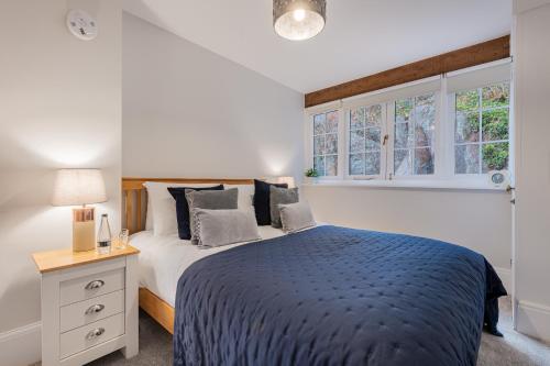 a bedroom with a bed with a blue blanket and windows at Rockwood- Grasmere family cottage with Hot tub in Grasmere