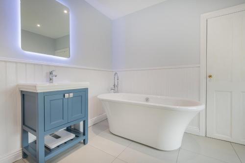 a bathroom with a tub and a sink and a mirror at Rockwood- Grasmere family cottage with Hot tub in Grasmere