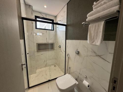 a bathroom with a toilet and a glass shower at Fenicia Palace Hotel in Varginha