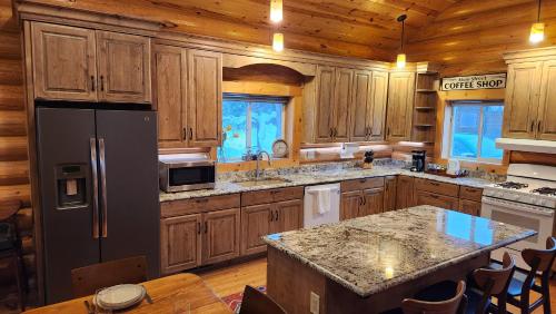 a kitchen with wooden cabinets and a black refrigerator at Beargrass Lodging & RV Resort in Hungry Horse