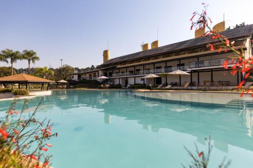 a large swimming pool in front of a building at Vale Das Águas Fazenda Resort in Santa Bárbara do Rio Pardo