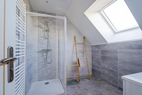 a bathroom with a shower and a skylight at Gite Les Portes De Montafilan in Corseul