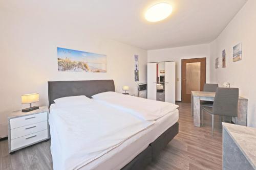 a bedroom with a large white bed and a desk at Hotel Hülsmann Garni in Niedersachsen-Stadland