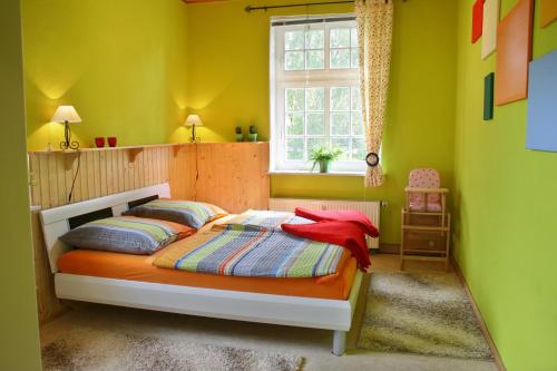 a bedroom with a bed with yellow walls and a window at Ferienwohnung Hoff in Göllingen