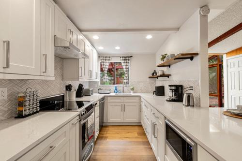 a large white kitchen with white cabinets and wooden floors at Spacious Mid Century Modern Sunroom Rambler in Shoreline