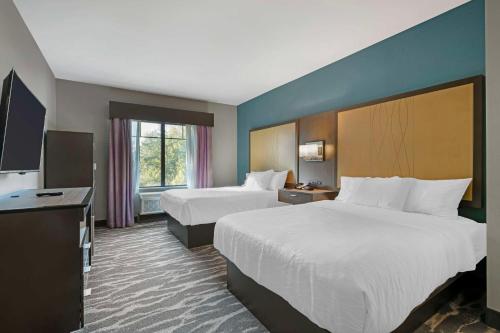 a hotel room with two beds and a flat screen tv at Best Western Plus Ruston Hotel in Ruston