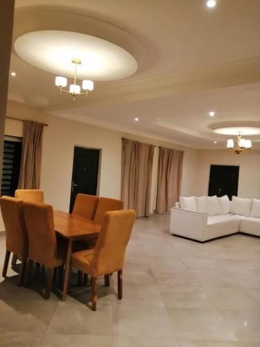a dining room with a table and chairs and a couch at Diaspora Holiday Villa in Aburi