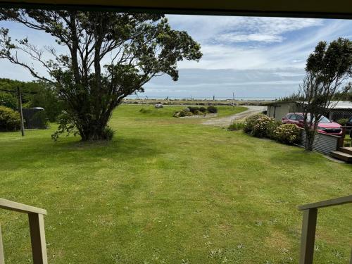 a yard with a tree in the middle of a field at On the Beach in Hokitika