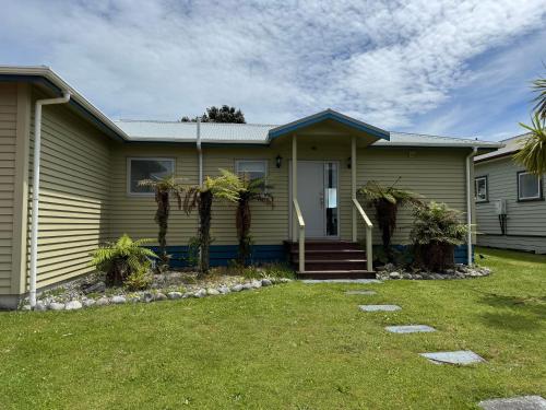 a house with palm trees in front of it at On the Beach in Hokitika