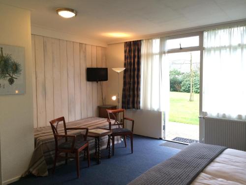 a hotel room with a table and chairs and a bed at Hotel Vierhouten in Vierhouten