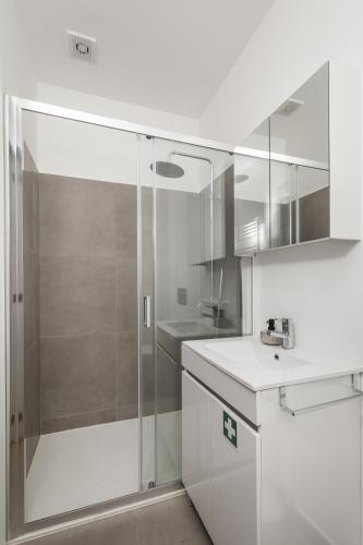 a white bathroom with a shower and a sink at Douro's Bridge View - Swimming pool in Vila Nova de Gaia