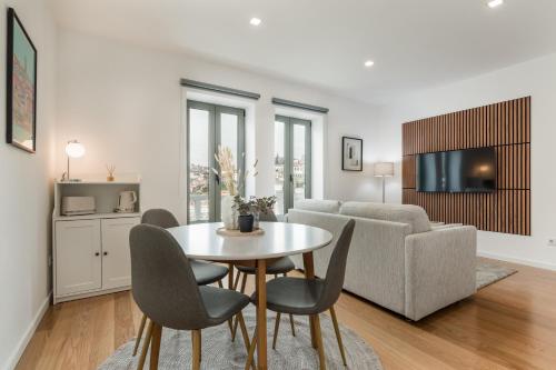 a living room with a table and chairs and a couch at Douro's Bridge View - Swimming pool in Vila Nova de Gaia
