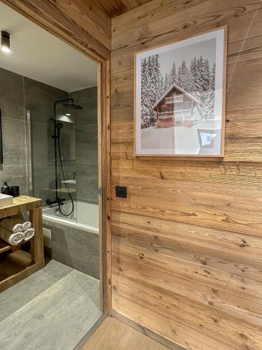La salle de bains est pourvue d'un mur en bois, d'une douche et d'un miroir. dans l'établissement Stella Megeve Palais garage, à Megève