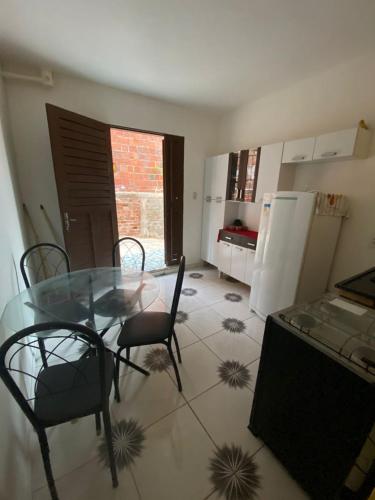 a kitchen with a glass table and chairs in a room at Chalé da Kikia in Icapuí