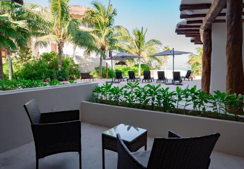 a patio with chairs and tables and palm trees at Beachfront Hotel Boutique DK in Holbox Island