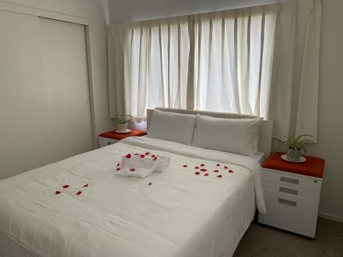 a bedroom with a white bed with red hearts on it at Happy room for you in Auckland