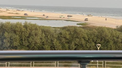 a view of a beach with people and the ocean at Luxury sea view apartment in Dahariz, Salalah شقة بحرية فاخرة بمنطقة الدهاريز السياحية بصلالة ظفار in Salalah