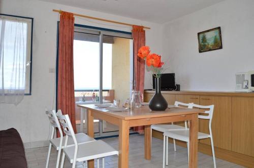 - une table à manger avec un vase orné de fleurs orange dans l'établissement SP280-124 Appt Studio Cabine 4 couchages SAINT PIERRE LA MER, à Saint Pierre La Mer